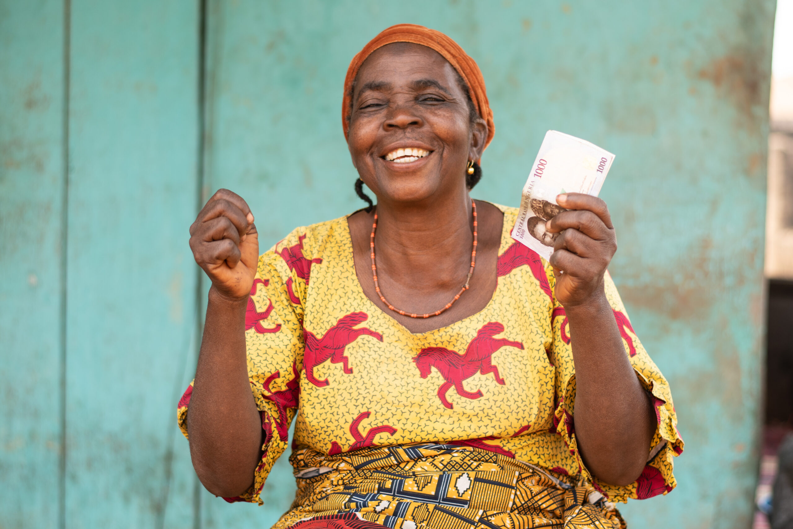Excited elderly African woman outdoors holding money